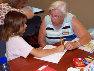 Volunteer grandmother helping girl with homework